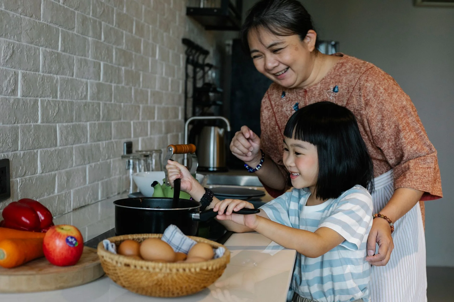 A grandmother and granddaughter preparing a meal together at home